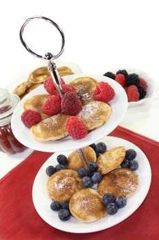 Poffertjes with raspberries and blueberries on a cake stand