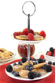 Poffertjes with raspberries and blueberries on a cake stand