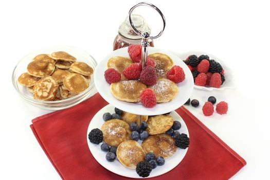 Poffertjes with raspberries and blueberries on a cake stand