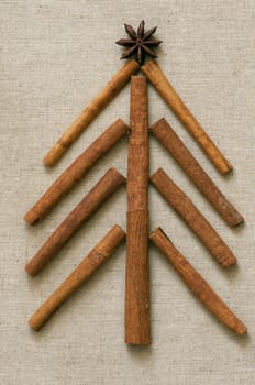Christmas tree made of cinnamon sticks on linen background