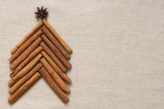 Christmas tree made of cinnamon sticks on linen background