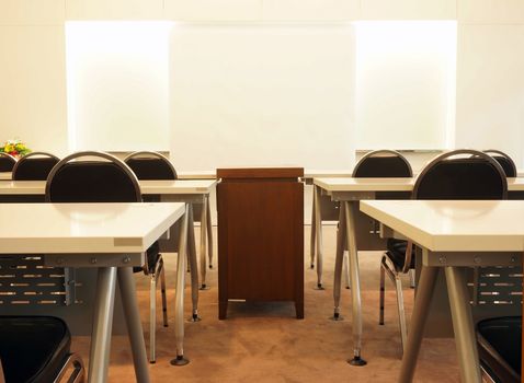 Classroom or meeting on campus, include tables, chairs and projection screen for slide presentation.                             