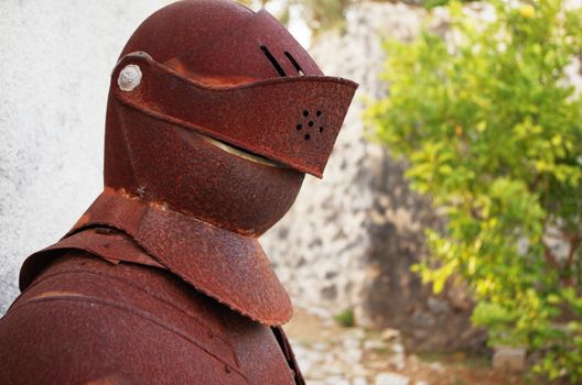 Photograph of an old and rusty knights iron armor from the middle ages in a fortress.