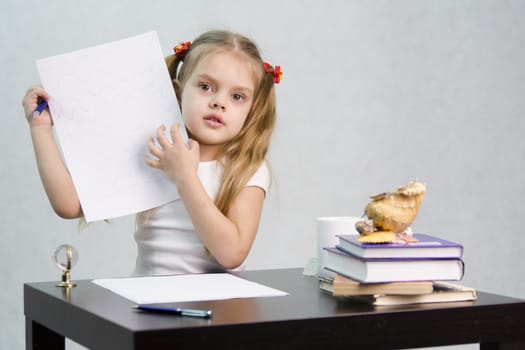girl sits at the table and shows written on a sheet of paper (Doodle). There are tombs of books, sheets of paper, a pen, glass globe, with a glass of tea, sea shell. The image of the writer.