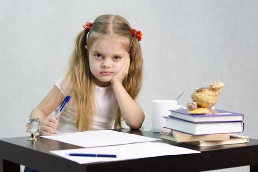 girl sits at a table and wrote on a sheet of paper. There are tombs of books, sheets of paper, a pen, glass globe, with a glass of tea, sea shell. The image of the writer