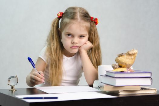 girl sits at a table and wrote on a sheet of paper. There are tombs of books, sheets of paper, a pen, glass globe, with a glass of tea, sea shell. The image of the writer