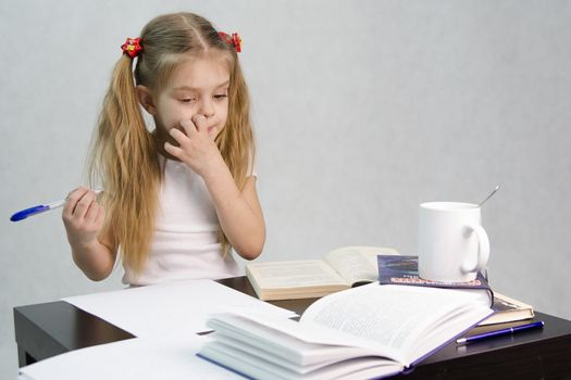 girl sits at a table and flips through the book and writes out the information you need. Next are still books, sheets of paper, a pen, a glass of tea. The image of a student, a pupil, a teacher and literary critic