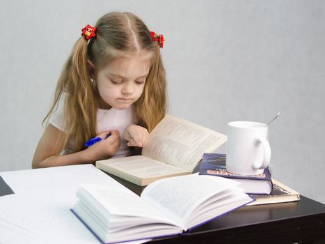 girl sits at a table and flips through the book and writes out the information you need. Next are still books, sheets of paper, a pen, a glass of tea. The image of a student, a pupil, a teacher and literary critic