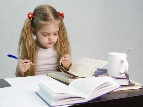 girl sits at a table and flips through the book and writes out the information you need. Next are still books, sheets of paper, a pen, a glass of tea. The image of a student, a pupil, a teacher and literary critic