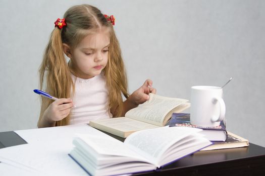 girl sits at a table and flips through the book and writes out the information you need. Next are still books, sheets of paper, a pen, a glass of tea. The image of a student, a pupil, a teacher and literary critic