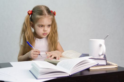 girl sits at a table and flips through the book and writes out the information you need. Next are still books, sheets of paper, a pen, a glass of tea. The image of a student, a pupil, a teacher and literary critic