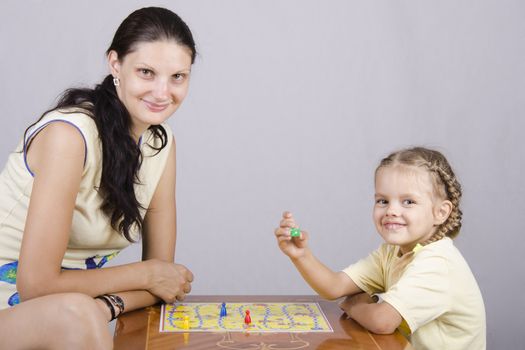 Mother and daughter sitting at a table and play a Board game