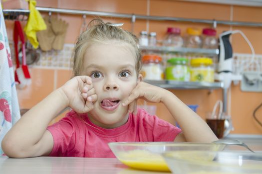 Girl five years eats porridge, sitting at the kitchen table.