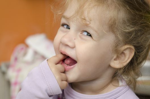 The little girl sits at a table and with enthusiasm eats a roll. Photo close up.