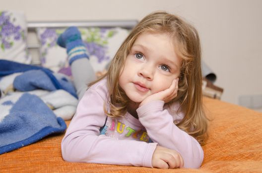 A girl laying on the couch and enthusiastically watching TV