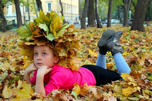 little girl lying on the yellow leaves in the park
