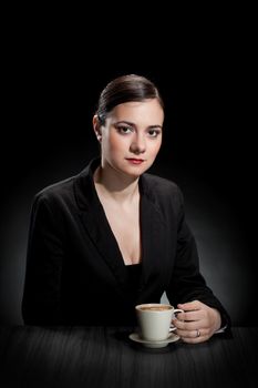 beautiful girl enjoying a cup of coffee on dark background