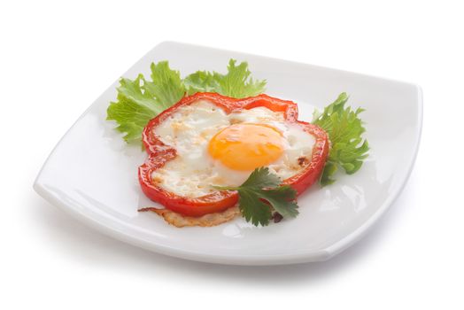 Fried egg with red pepper, fresh lettuce and parsley on the white plate