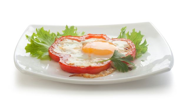 Fried egg with red pepper, fresh lettuce and parsley on the white plate