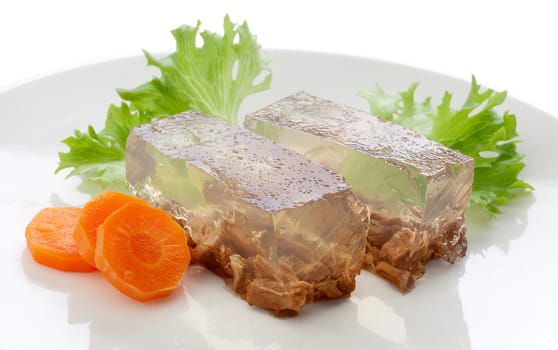 Two pieces of beef aspic with green fresh parsley and orange carrot on the white plate