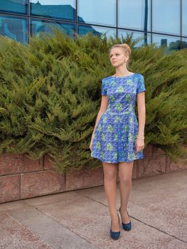 Young girl blonde in blue short dress to utmost high-heeled