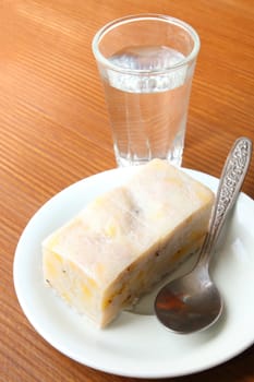 Thai dessert made from banana and coconut serve with a glass of water.
