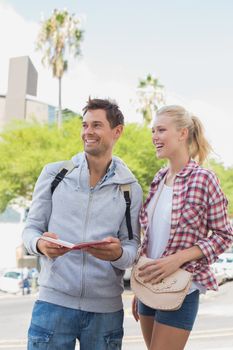 Young tourist couple consulting the guide book on a sunny day in the city