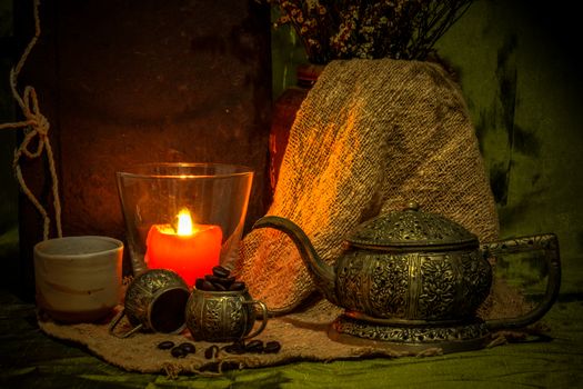 Still life with candle and ancient silver teapot.