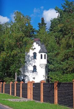 A country White cottage in the form of a tower in the trees 