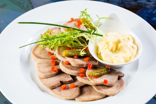 boiled beef tongue sliced on a plate with dill
