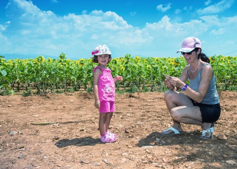 Mother and daughter enjoying outdoor with sunflowers field.