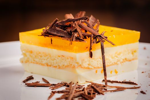 Layered delicious cheesecake with milk and orange jelly on plate