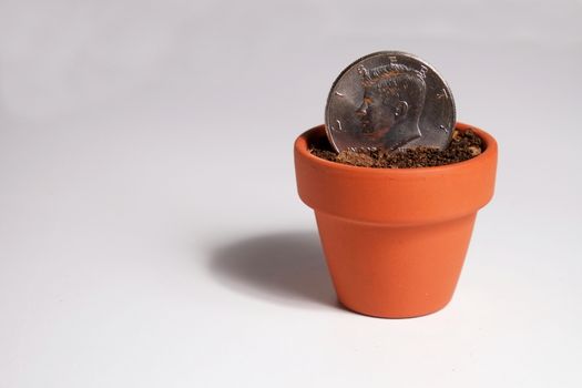 An American Dollar coin planted in a clay pot