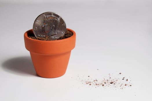 An American Dollar coin planted in a clay pot. Isolated objects and showing debris on the table surface