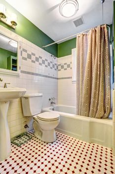 Bathroom inteiror with green wall and white tile trim. Bath tub with beige curtain