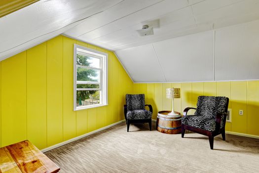 Bright yellow room with white vaulted ceiling. Sitting area with two black chairs and decorative table