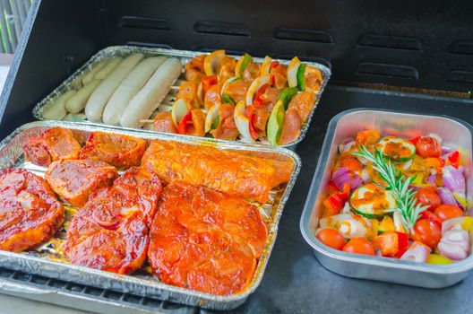 Barbecue food, barbecue meat marinated in a foil dish on a grill.