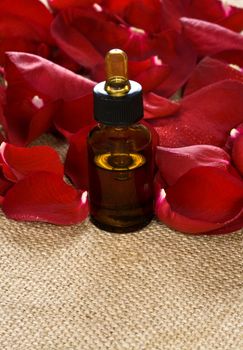 Red rose petals and massage oil on sackcloth
