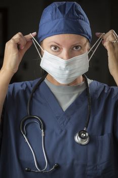 Attractive Female Doctor or Nurse Putting on Protective Face Mask.