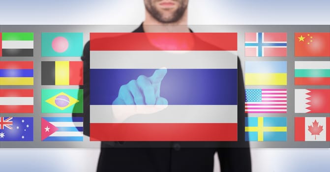 Hand pushing on a touch screen interface, choosing language or country, Thailand