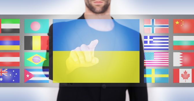 Hand pushing on a touch screen interface, choosing language or country, Ukraine