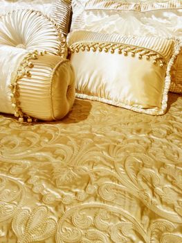 Bed with luxurious silky bedding and decorative cushions.