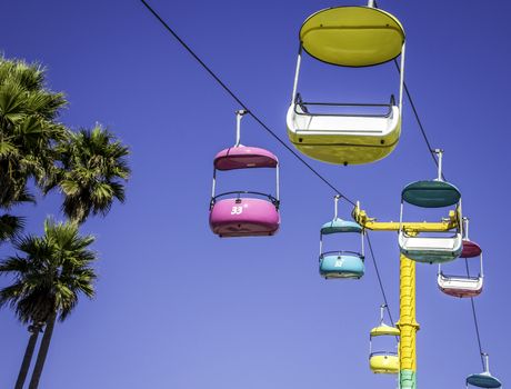 Brightly colored striking cable cars and palm tree set against a deep blue sky