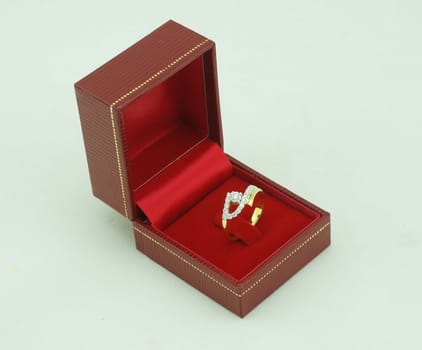 Diamond ring, the ring is made of gold placed in a red velvet box.                             