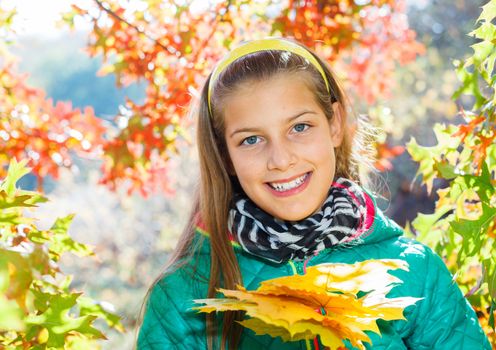 Portrait of Adorable cute girl with autumn leaves in the beauty park