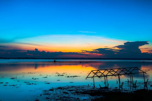 sunset sky over lake or river and home with flood at twilight