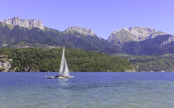 A sailing boat on a stunning blue lake with a fabulous mountainous backdrop