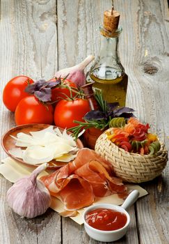 Arrangement of Raw Rotini Pasta, Tomatoes, Spices, Smoked Ham and Olive Oil isolated on Rustic Wooden background