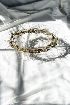 crown of thorns reminds the passion of the christ. resting on a white linen cloth with an olive branch