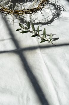 crown of thorns reminds the passion of the christ. resting on a white linen cloth with an olive branch